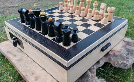 Hêtre et chêne massifs, assemblage d'angles à queues d'aronde à recouvrement d'onglets, plateau une face échecs et seconde face dames. Tiroirs avec casiers de rangement pour les pièces.